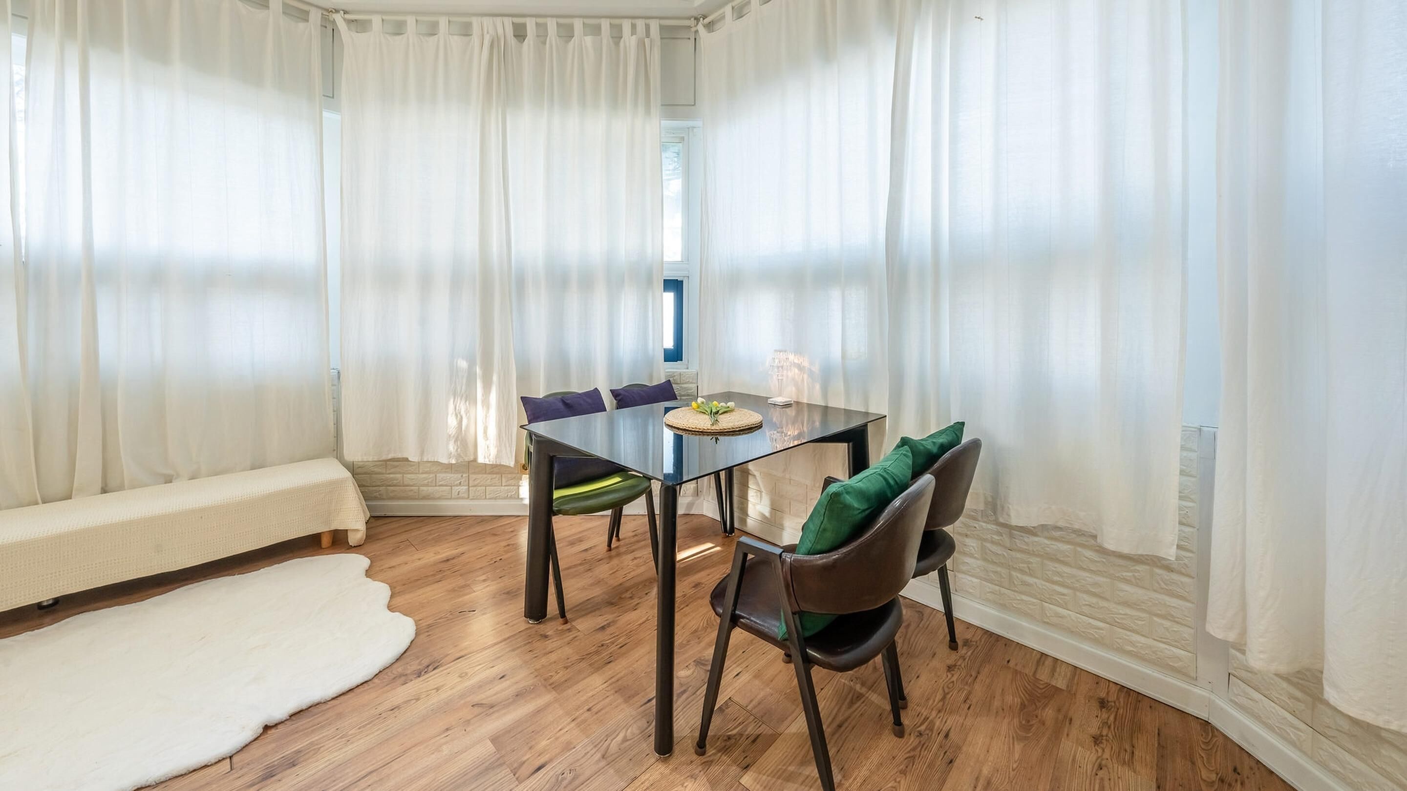A dining area with a glass table, chairs, and a bench.