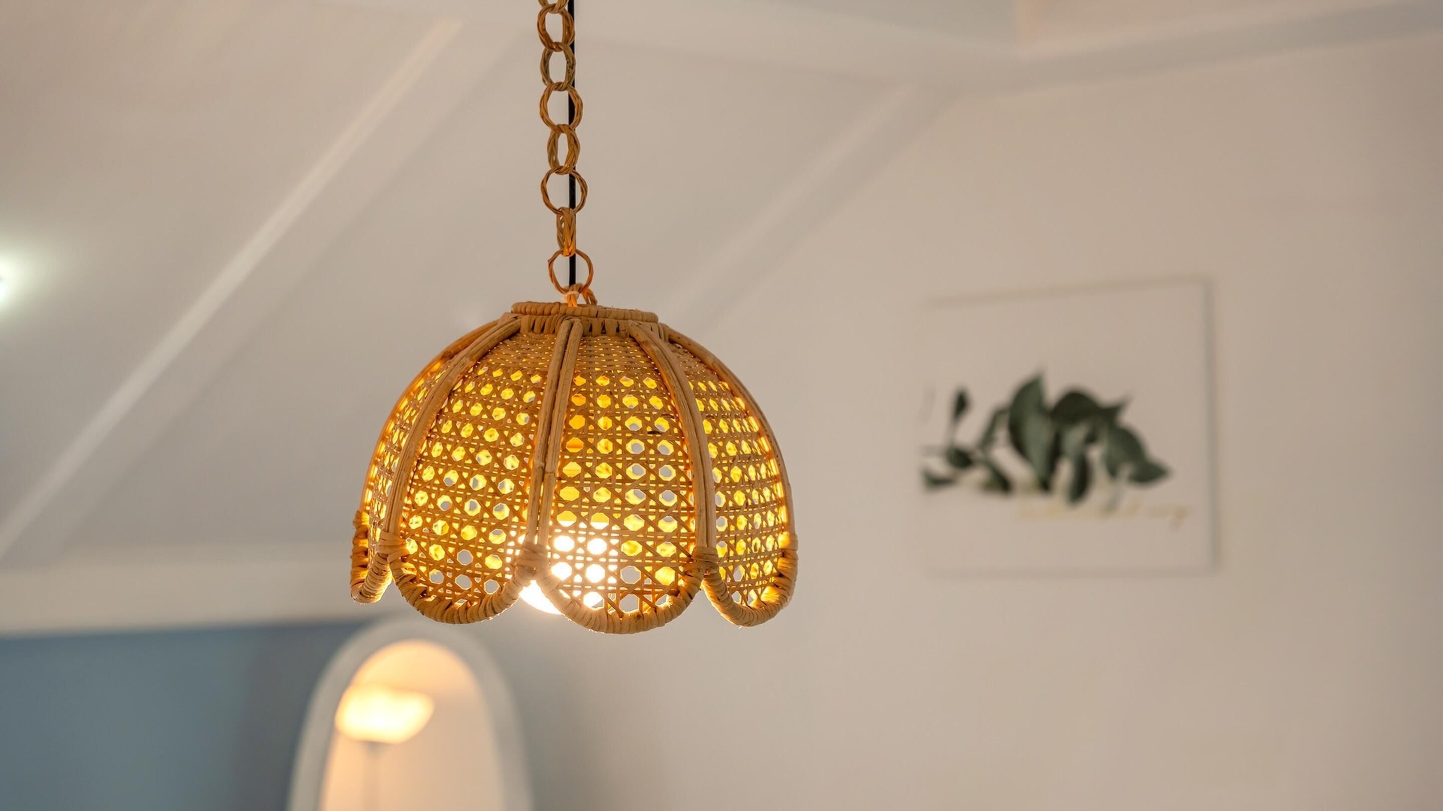 A hanging lantern with a geometric pattern, a framed artwork on the wall, and a blurred light source in the background.