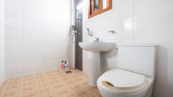 A bathroom with white tiles, a beige floor, a white sink, and a toilet.