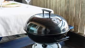 Een roestvrijstalen grill met deksel, geplaatst op een tafel met een wit tafelkleed.