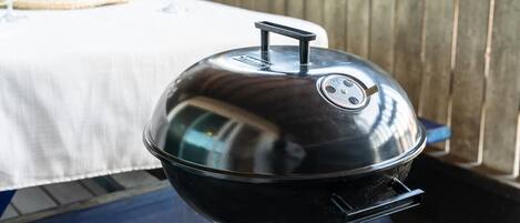 A stainless steel grill with a lid, placed on a table with a white tablecloth.