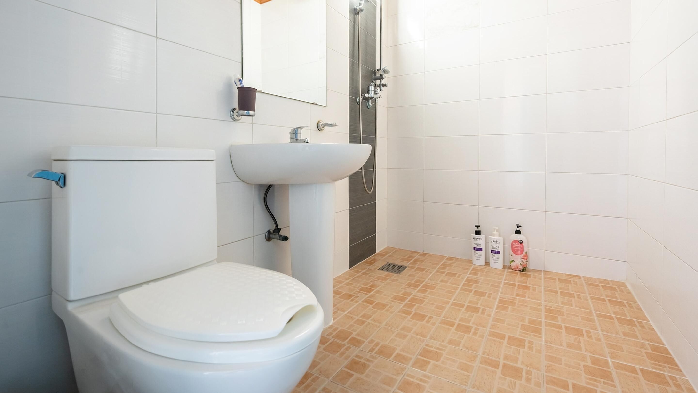 A bathroom with a toilet, sink, shower, and tiled floor.