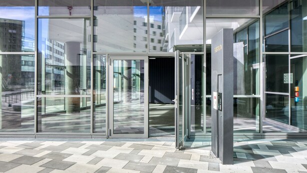 A modern building entrance with glass doors and a tiled floor. - Favoriten Studio w Gym & Bike Storage, nr Metro by Blueground (Vienna)