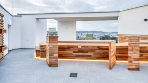 A rooftop terrace with wooden benches and a city view. - Favoriten Studio w Gym & Bike Storage, nr Metro by Blueground (Vienna)
