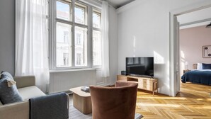 A modern living room with a large window, a flat-screen TV, a sofa, a coffee table, and a wooden floor.