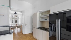 A modern kitchen with white cabinetry, a black refrigerator, and a dining area with a table and chairs.