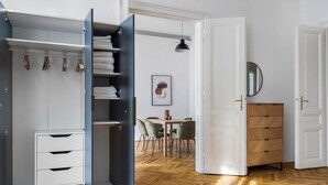 A room with a wardrobe, a dining area, and a wooden cabinet.