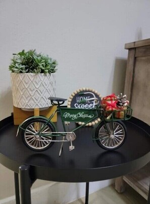 Ein dekoratives Fahrrad mit einem Schild, auf dem 'HOME sweet home' und 'Frohe Weihnachten' steht, auf einem schwarzen Tisch.