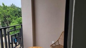 A balcony with two wicker chairs and a small wooden table.