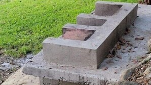A concrete staircase leading up to a grassy area with a river in the background.
