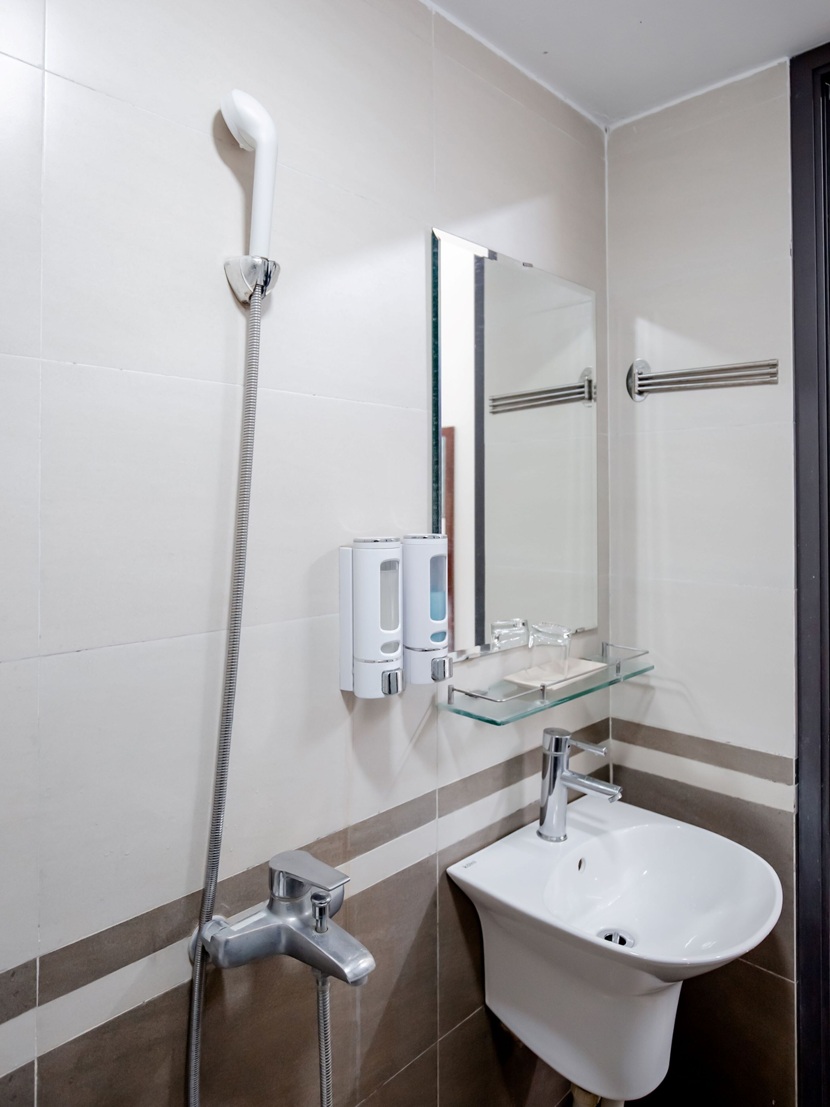 A bathroom with a shower, a sink, a mirror, and a towel rack.