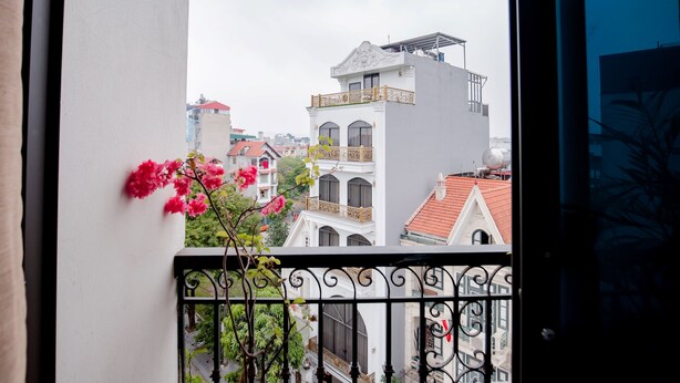 Un balcón con barandilla de hierro forjado, con vistas a un paisaje urbano con edificios de diversos estilos arquitectónicos.