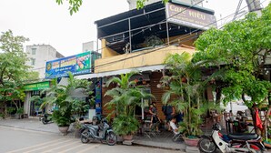 Vista de la calle con un café llamado Cafe Hieu, un letrero de King Deli y varias plantas en macetas.