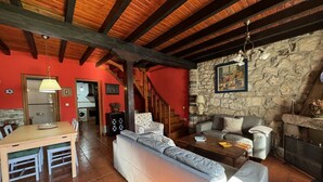 Un'ampia zona giorno con soffitto in legno, parete in pietra e camino.