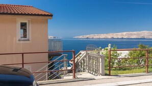 A coastal building with a tiled roof, a small window, and a staircase leading to a balcony overlooking the sea. - Lovely apartment for 3 guests with A/C, WIFI, TV and balcony (Senj)