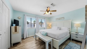 A bedroom with a bed, bedside tables, a bench, a ceiling fan, and a window with curtains. - Sea Star, Gulf-side townhome, 2-minute walk to the beach (Navarre)