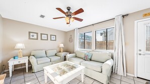 A living room with a ceiling fan, two sofas, a coffee table, and a door with a window. - Sea Star, Gulf-side townhome, 2-minute walk to the beach (Navarre)