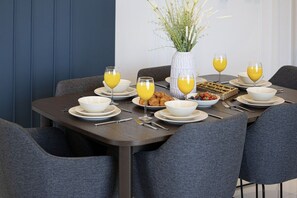 A dining table set with plates, bowls, glasses of orange juice, and a vase with flowers. - 2BR |Sea & City Views |Infinity Pool |High Floor (Dubai)