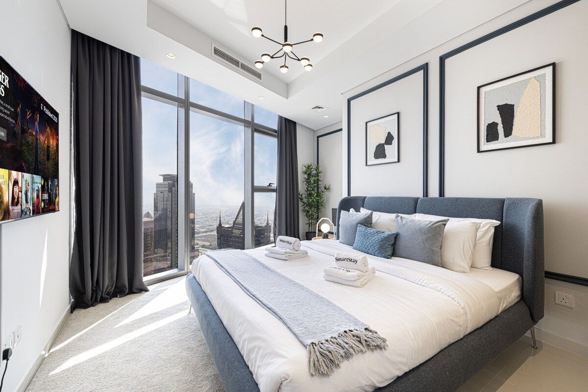 Une chambre d’hôtel moderne avec un grand lit, une vue sur la ville et des œuvres d’art accrochées aux murs.