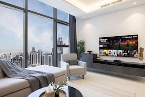 Ein modernes Wohnzimmer mit großem Fenster, einem Flachbildfernseher und Blick auf die Stadt.