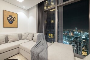 A modern living room with a large window offering a cityscape view at night. - 2BR |Sea & City Views |Infinity Pool |High Floor (Dubai)