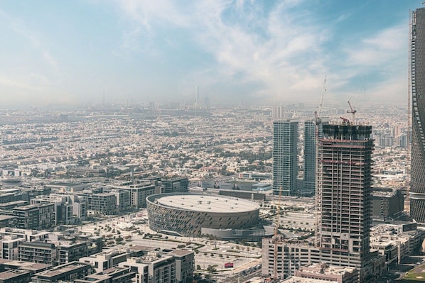 A cityscape with a prominent circular building, high-rise buildings, and construction cranes.