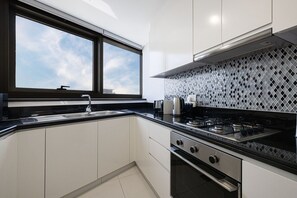 A modern kitchen with a large window, a gas stove, and white cabinets. - 2BR |Sea & City Views |Infinity Pool |High Floor (Dubai)