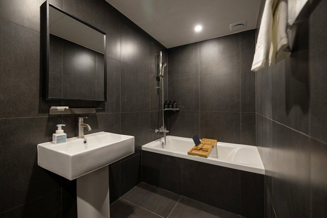 Un baño moderno con un lavabo blanco, una bañera y un espejo grande.