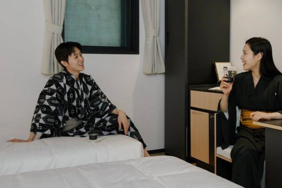 A hotel room with a bed, a desk, and a window with curtains.