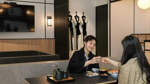 A modern dining area with a flat-screen TV mounted on the wall, a wooden panel wall, and a seating arrangement with a table set for two. - Mitasuya Ryokan Hotel Incheon by Anook (Incheon)