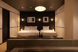 Una habitación de hotel moderna con dos camas, una lámpara central y apliques de pared.