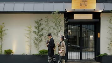 Traditional Japanese architecture with a dark facade and a large signboard featuring the hotel's name.