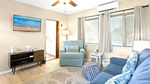 A living room with a ceiling fan, a TV, a blue armchair, a sofa, and a small side table. - easy access to beach, large family retreat, huge outdoor area (Treasure Island)
