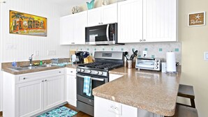 A kitchen with white cabinets, a microwave, stove, and a toaster. - easy access to beach, large family retreat, huge outdoor area (Treasure Island)