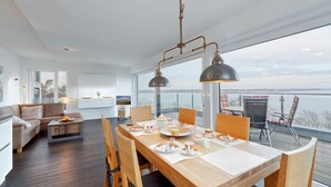 A modern living room with a dining area, large windows, and a view of the water. - 2 bedroom nice apartment in Eckernförde (Eckernförde)