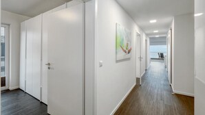 A hallway with white walls, a wooden floor, and a door leading to a balcony with a view. - 2 bedroom nice apartment in Eckernförde (Eckernförde)