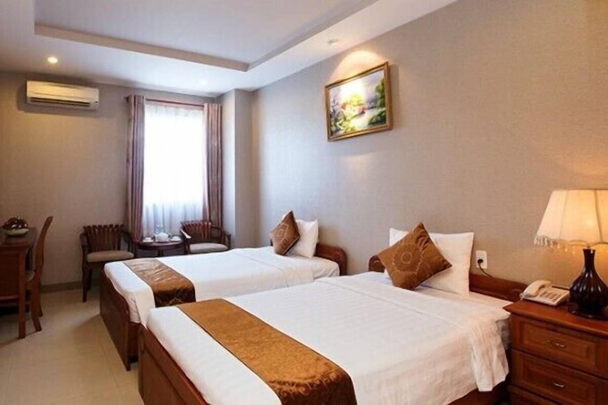 Una habitación de hotel con dos camas, un escritorio, una silla, un televisor y un cuadro en la pared.
