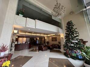Un vestíbulo de hotel con una recepción, zona de estar y un árbol de Navidad decorado.