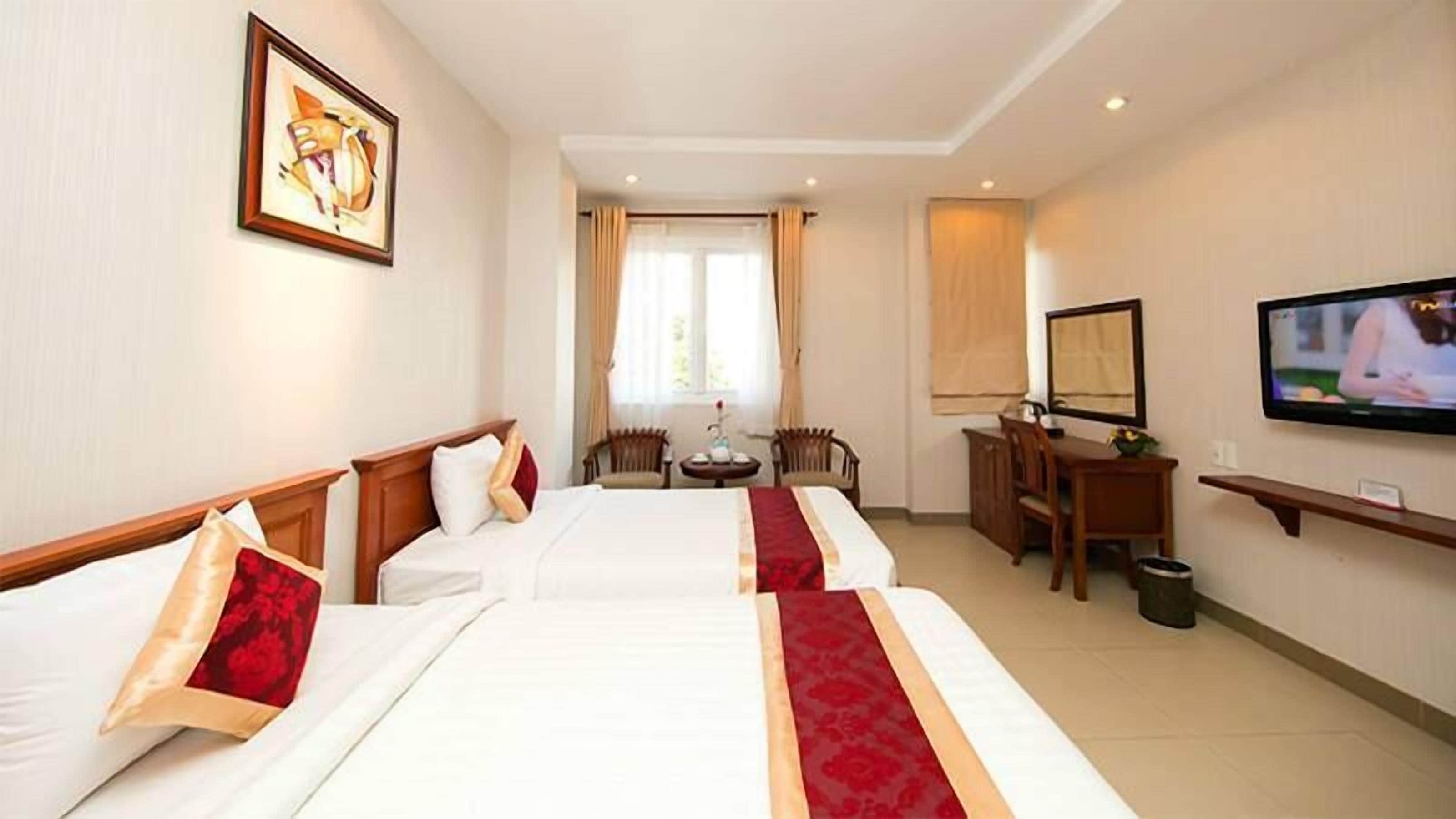 A hotel room with two beds, a desk, a chair, a television, and a window with curtains.