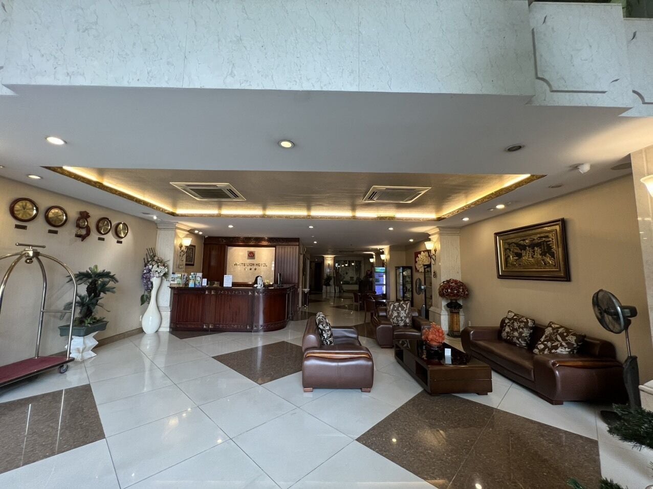 A hotel lobby with a reception desk, seating area, and a large mirror.