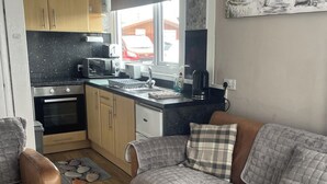 A compact kitchen with a built-in oven, microwave, and toaster. There is a window above the sink, and a small rug on the floor.