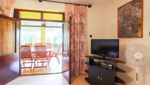 A living room with a TV, a fan, and a dining area with chairs and a table. - Stunning private villa for 8 people with WIFI, TV, patio and pets allowed (Marcali)