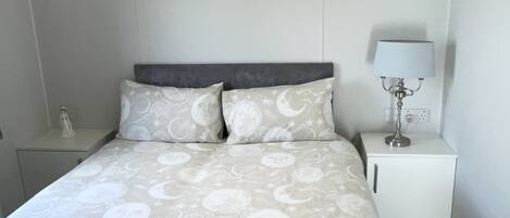 A bedroom with a bed, nightstands, and a lamp.