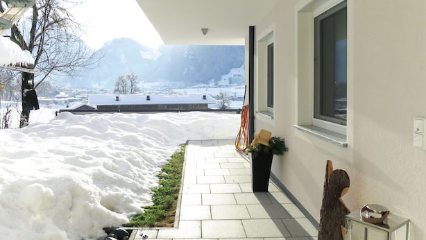 Ein verschneiter Weg, der zu einem Gebäude mit Bergblick führt.
