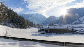 Eine verschneite Berglandschaft mit einem Gebäude im Vordergrund.
