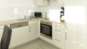 Eine moderne Küche mit weißen Schränken, einem Geschirrspüler, einer Mikrowelle, einem Backofen und einer Kaffeemaschine.
