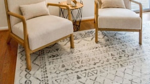 Two armchairs with cushions, a lamp on a side table, and a decorative mirror on the wall.