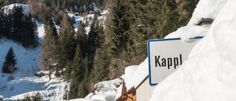 A snow-covered mountain village with wooden buildings and a sign reading "Kapp".