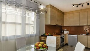 A modern kitchen with wooden cabinets, a glass dining table, and a bowl of fruit. - Beautiful apartment for 4 guests with pool, WIFI, A/C, TV and terrace (Santa Isabel)