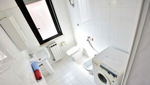 A modern bathroom with a sink, toilet, and washing machine. - Nice apartment for 4 guests with WIFI, TV, balcony and pets allowed (Silvi)